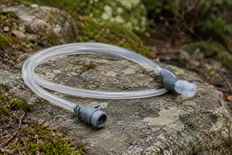 Tube d’hydratation clair HydraPak avec raccord rapide et valve à morsure posé sur une pierre