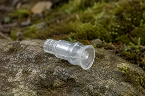 Valve de morsure Osprey en plastique transparent posée sur une pierre en sous-bois