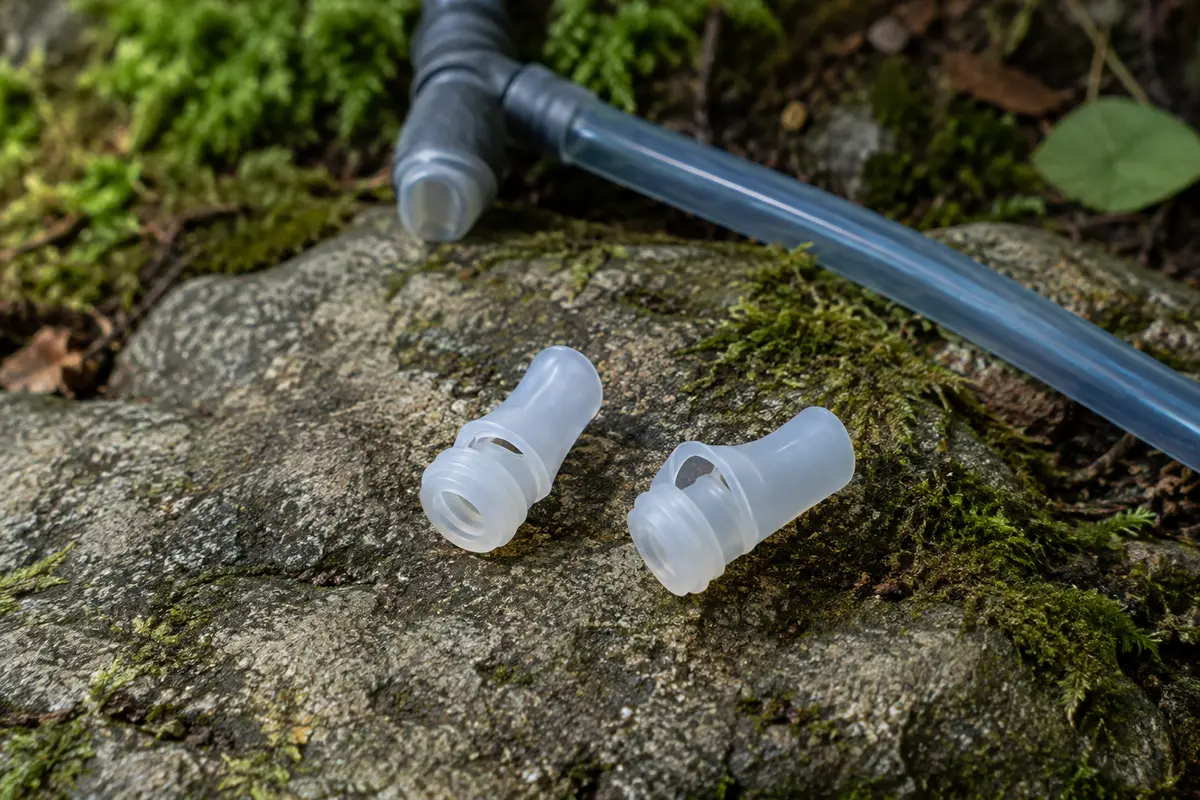 Deux embouts de valve à mors en silicone posés près d’un tube d’hydratation sur une pierre de sentier